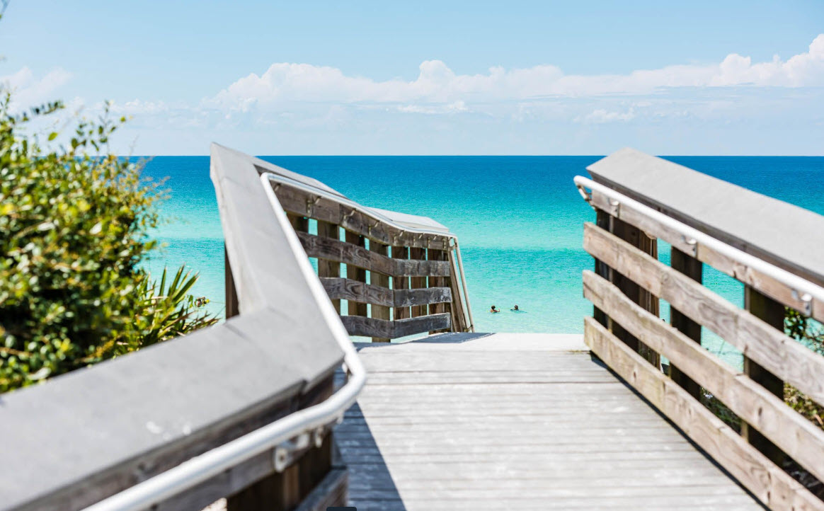Wooden boardwalk opening onto a bright white beach