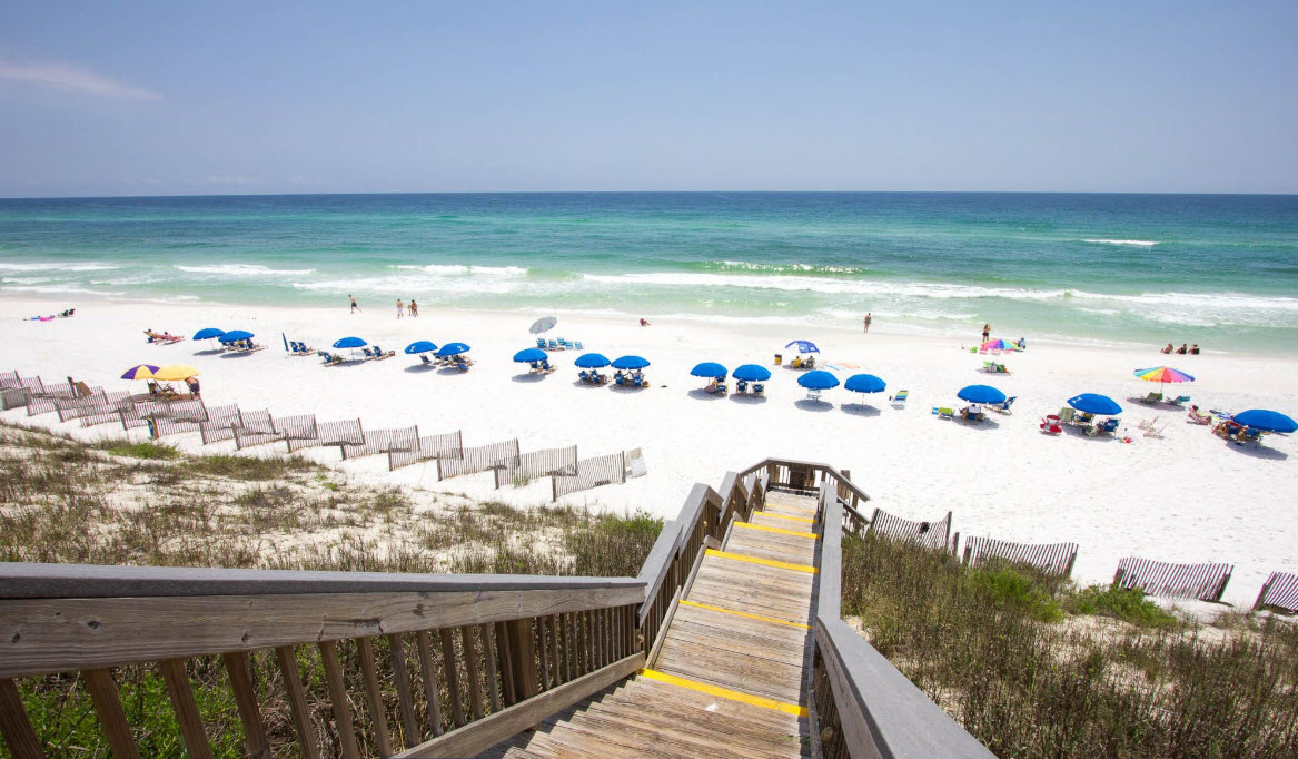 Beach stairs leading toward rows of blue umbrellas