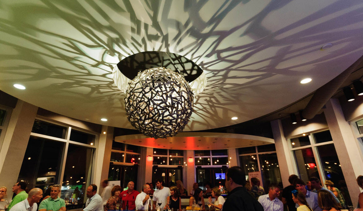 Busy restaurant dining room beneath a sculptural light fixture