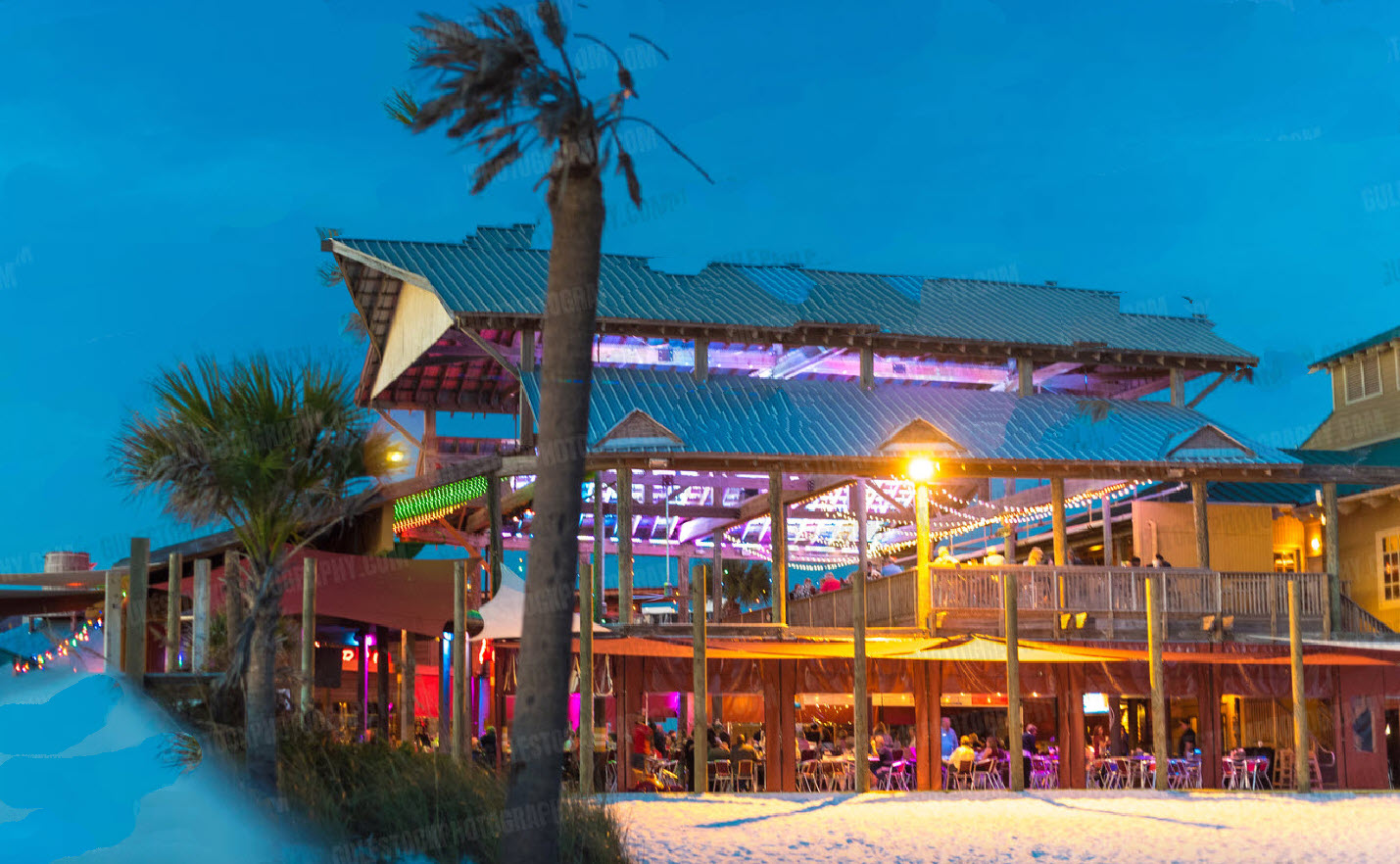 Colorful beachfront restaurant glowing at dusk