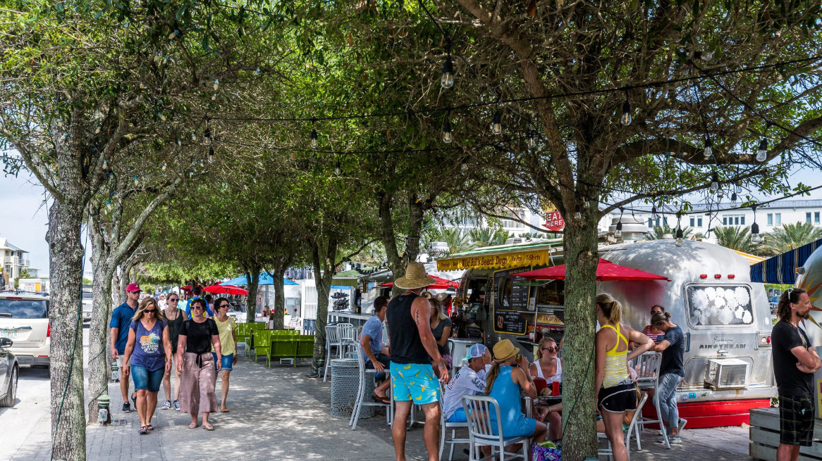Families browsing a shaded outdoor market