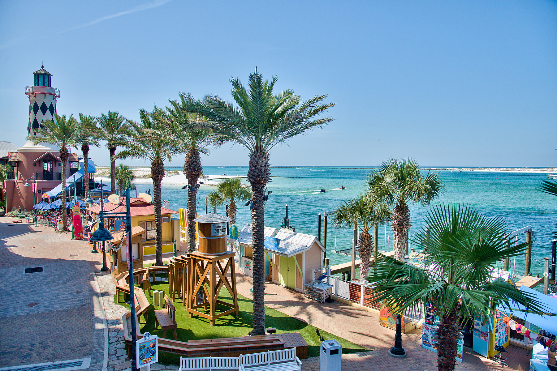 Waterfront boardwalk with a playground and palm trees