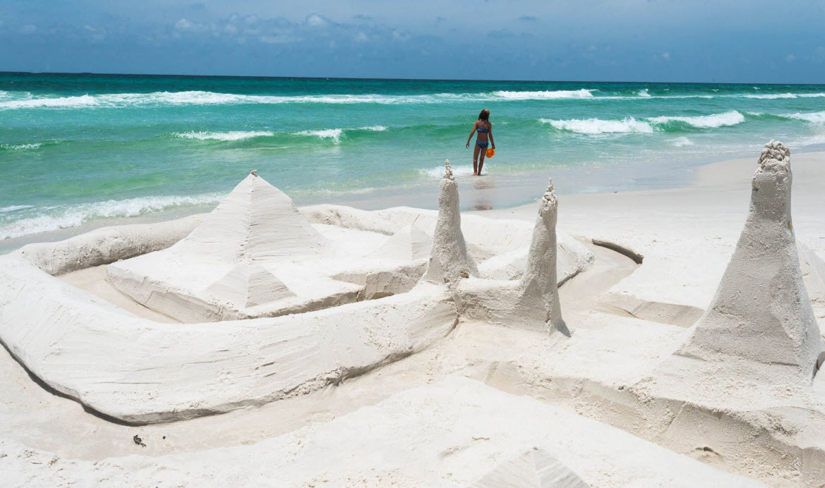 Child standing behind an elaborate sandcastle