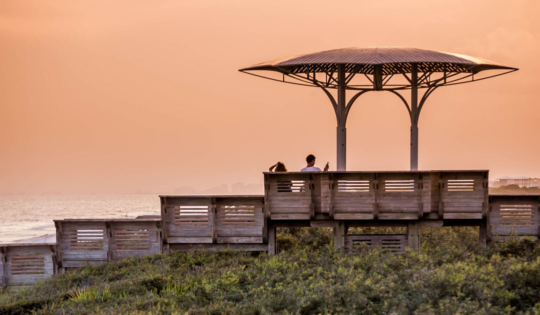 Two people watching sunset from a beach gazebo