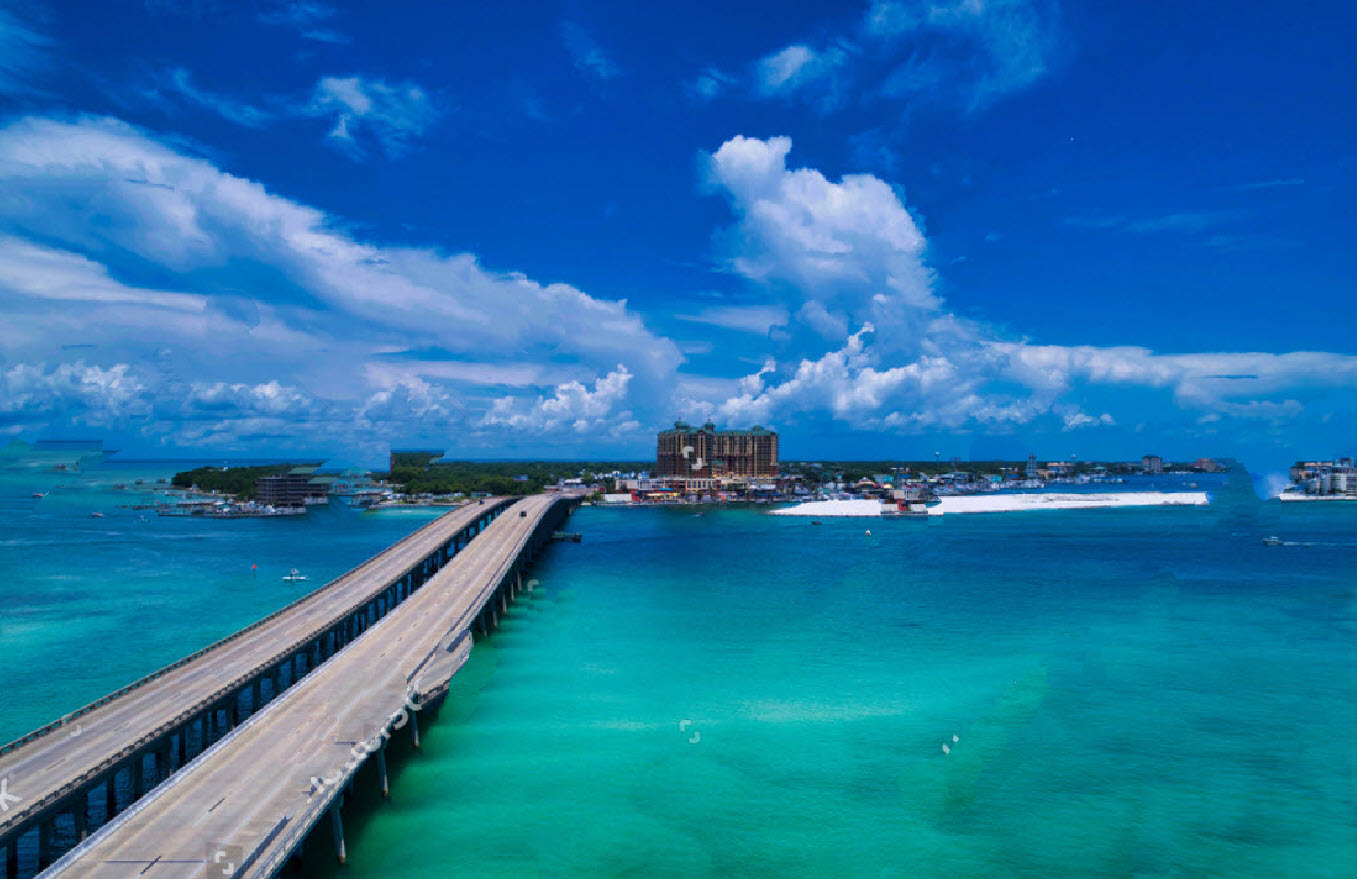 Long bridge crossing an emerald inlet beneath dramatic clouds