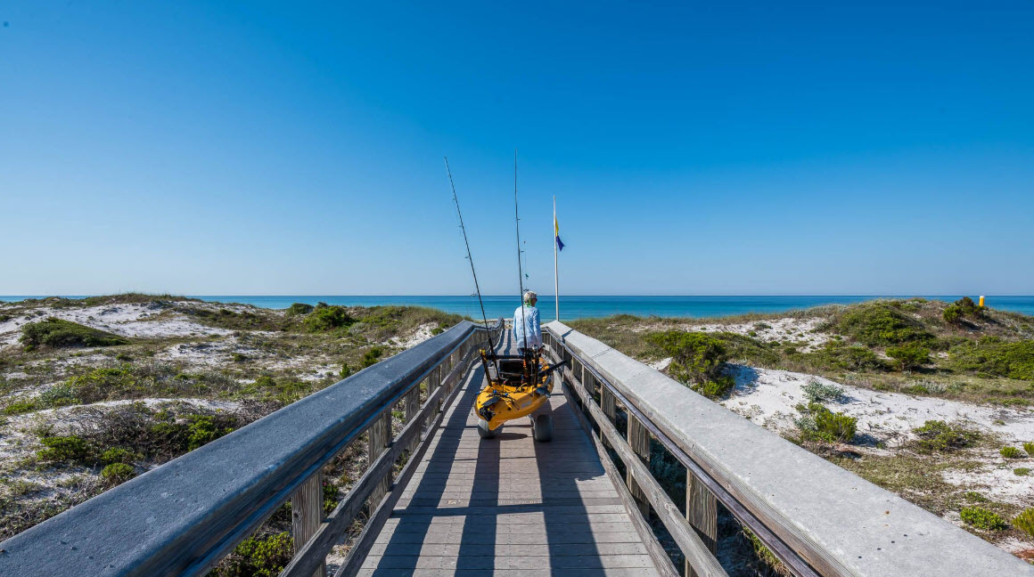 Bicycle resting on a boardwalk leading to the beach