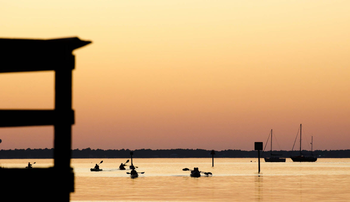 Paddlers crossing calm water at sunset