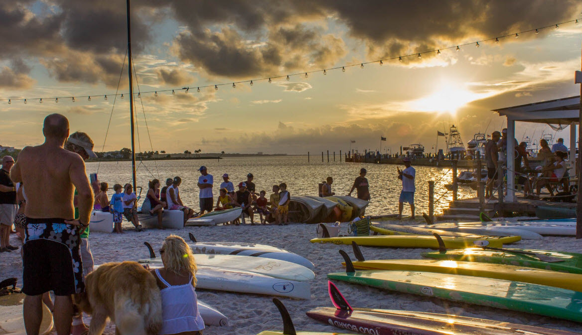 Group gathering beside kayaks at sunset