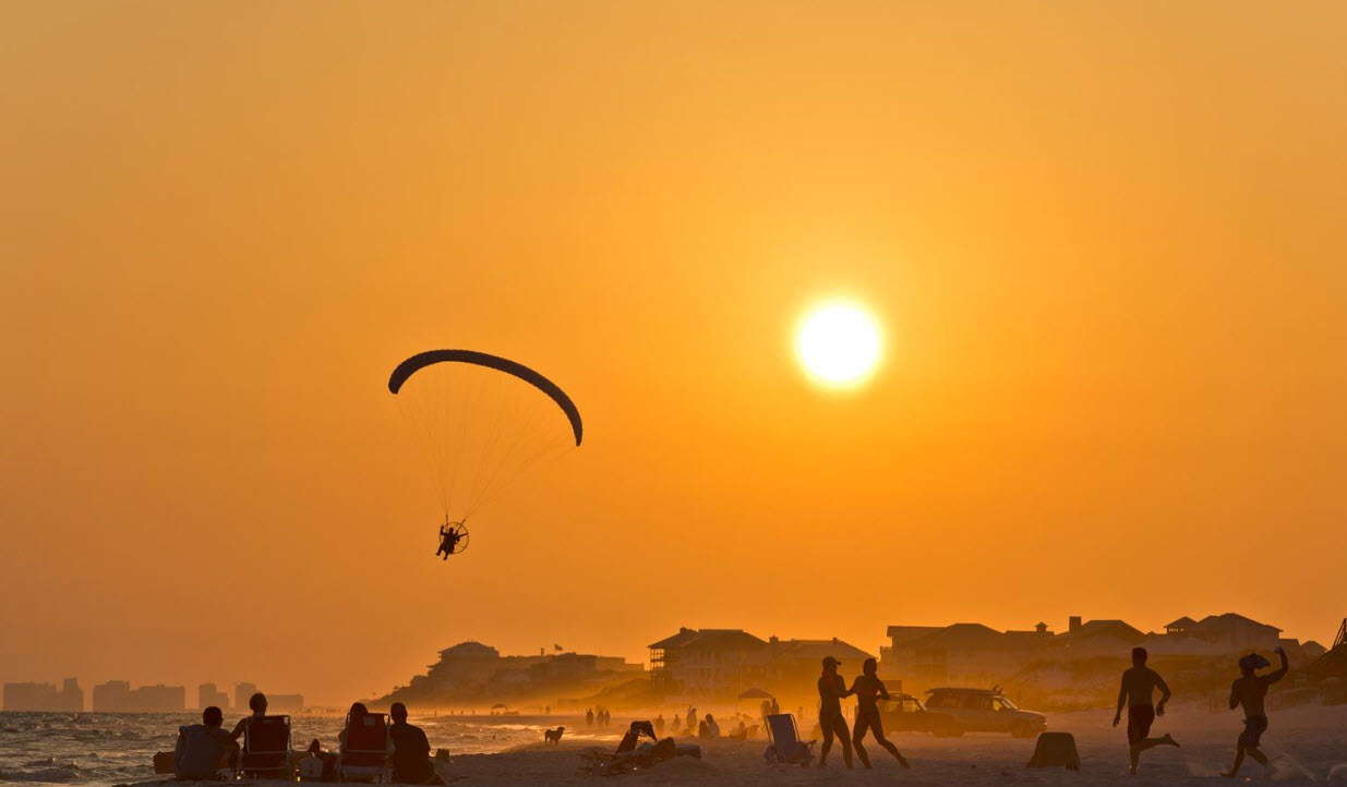 Parasailer silhouetted against an orange sunset