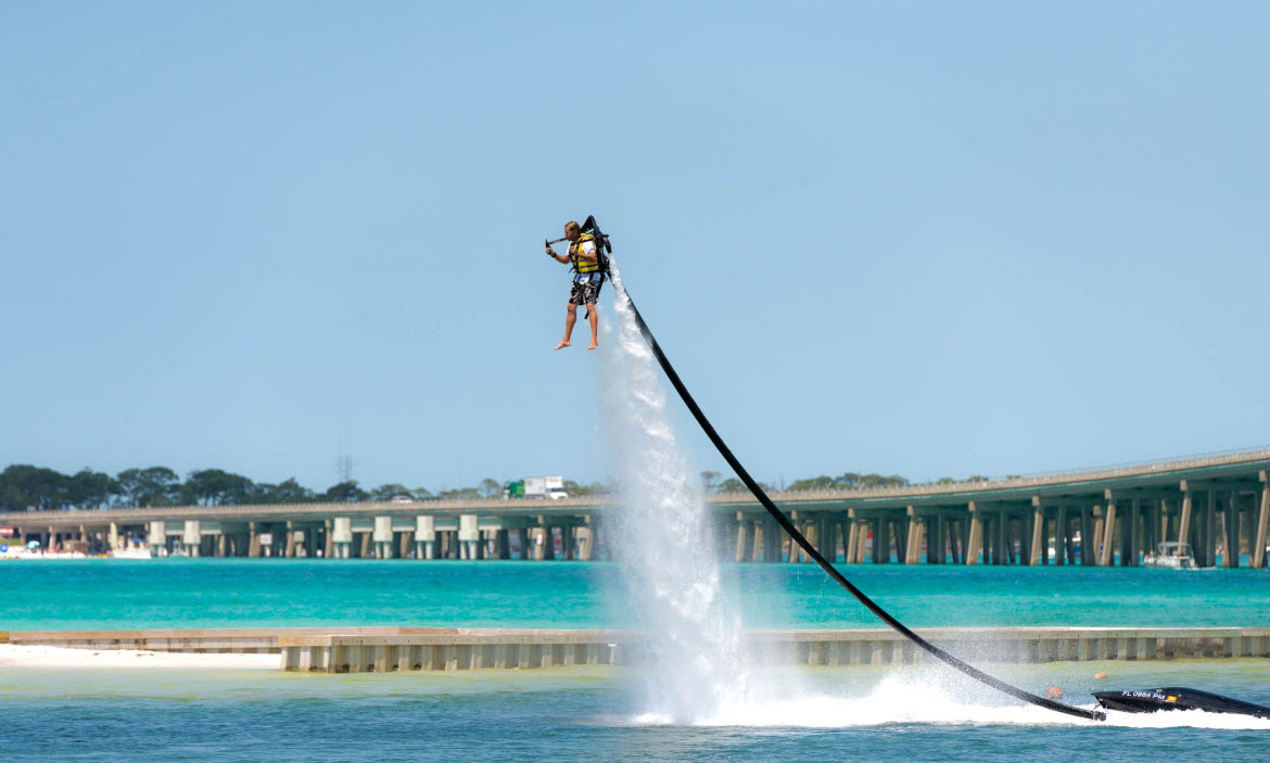 Flyboard rider rising above the water near a pier